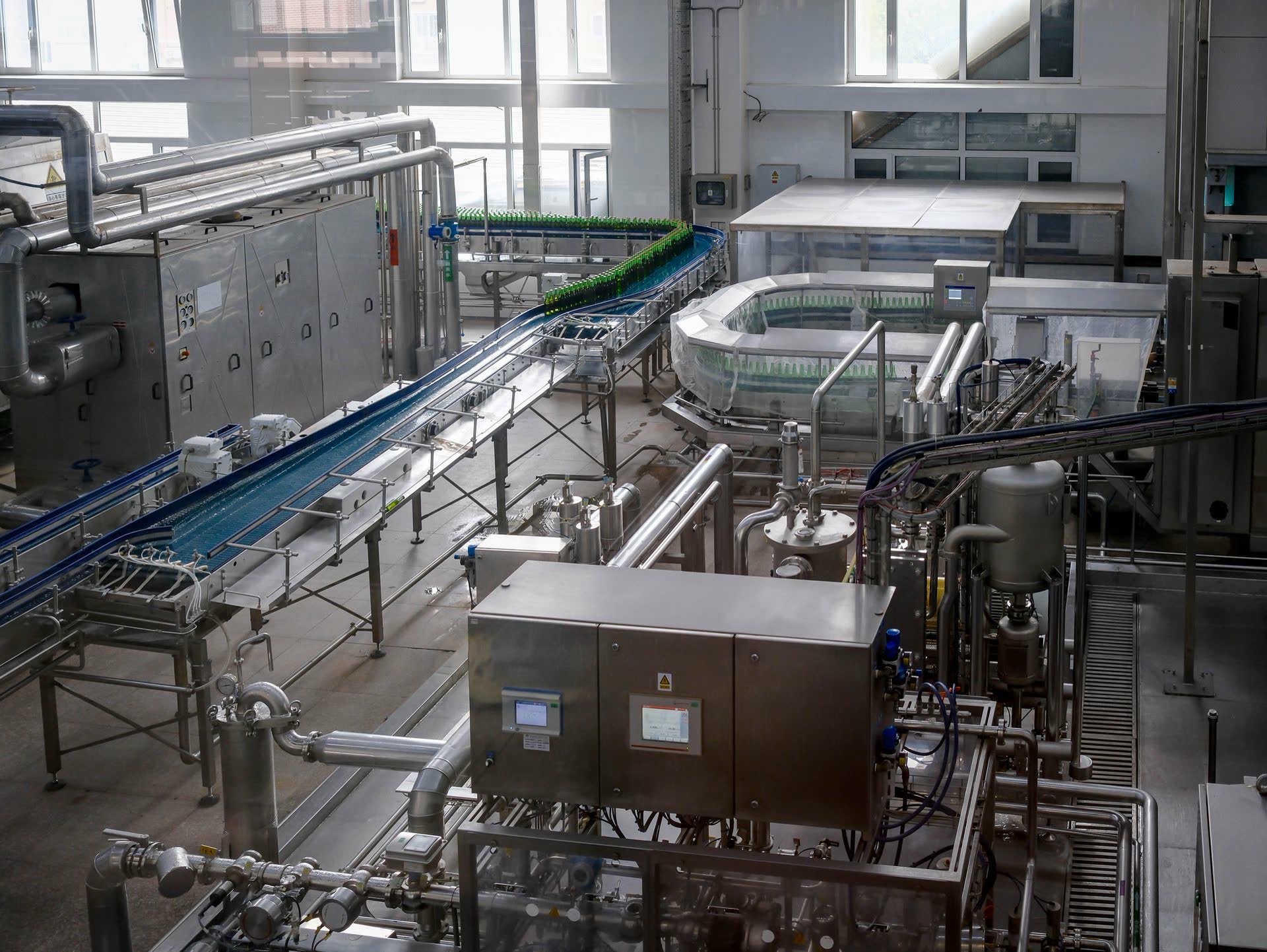 Automated beverage bottling hall with glass bottles moving along conveyors